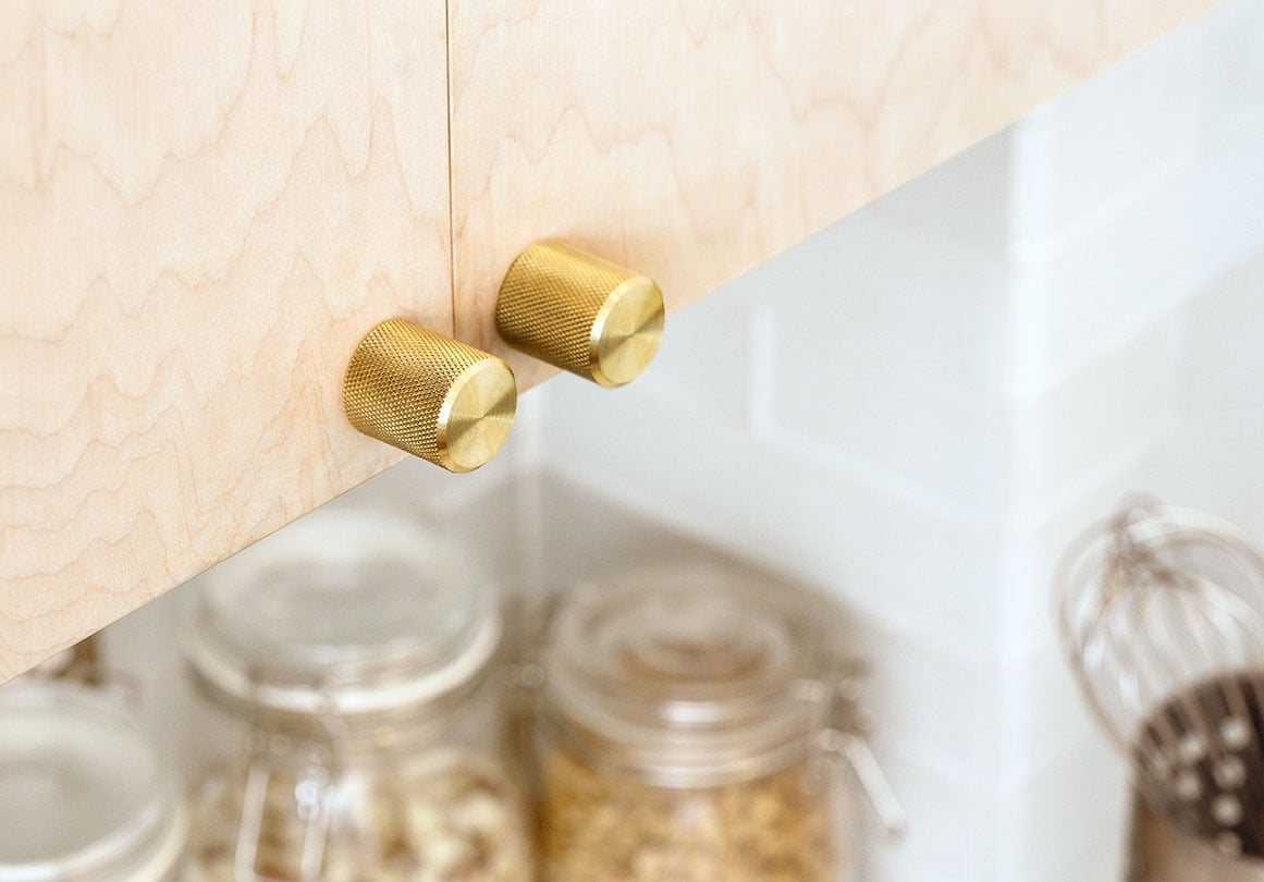 Kor Cabinet Knob in Brass finish  installed on a kitchen cabinet.