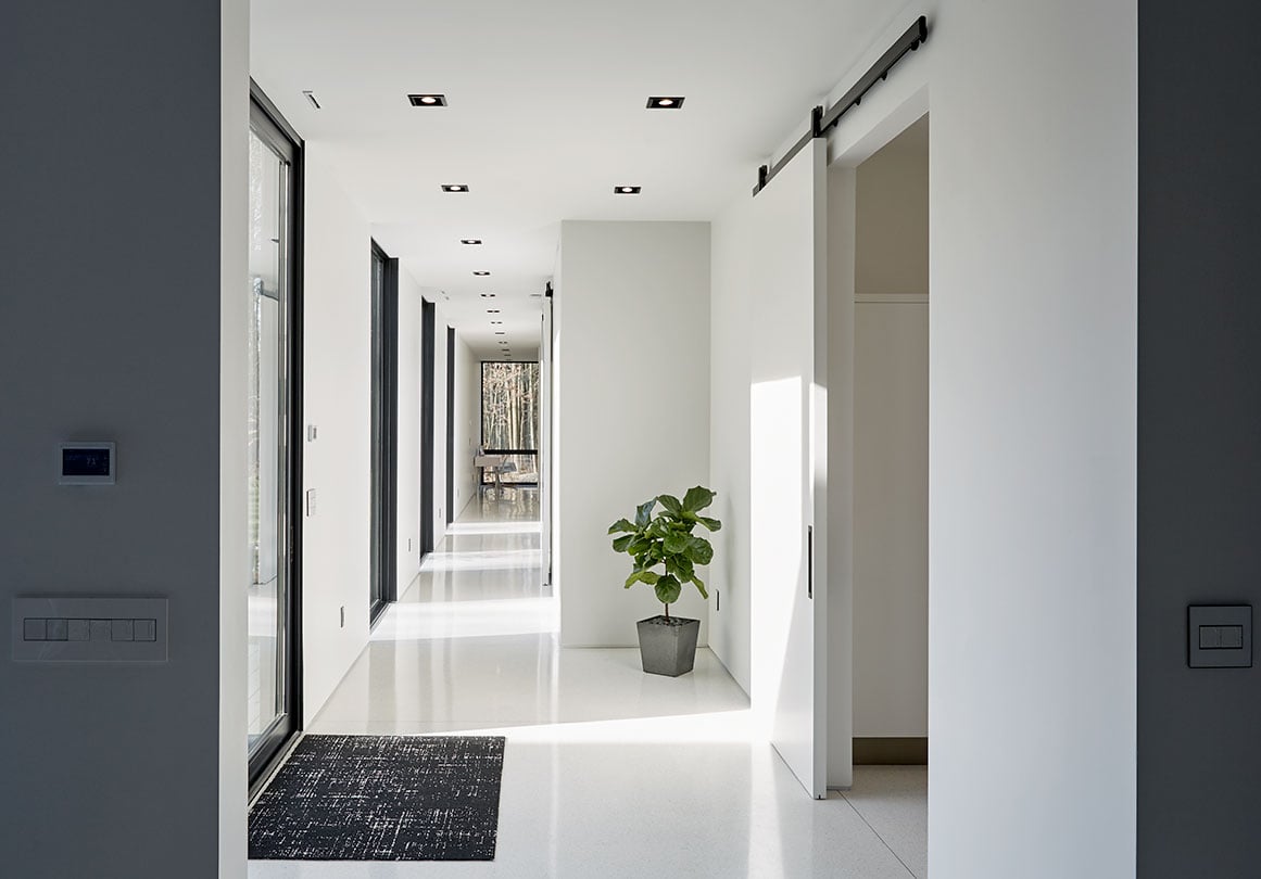 Black sliding door hardware makes a statement in a modern white interior.