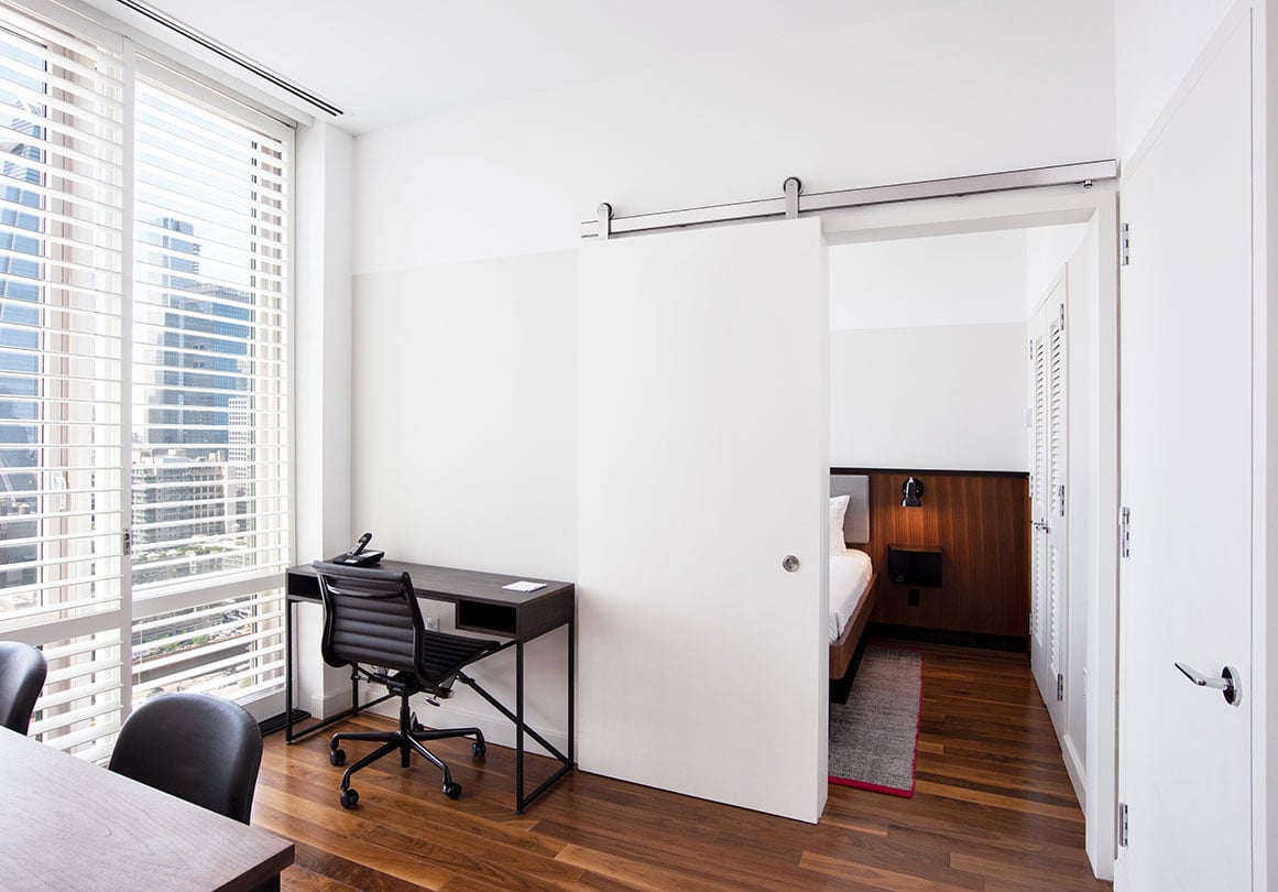 Krownlab modern sliding door hardware in brushed stainless finish with white door over bedroom entry